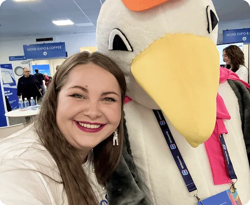 Ein Mitglied des Collaborator-Teams posiert mit der BrightonSEO-Möwenmaskottchenfigur beim Event 2025.