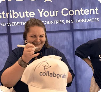 Ein Mitglied des Collaborator-Teams gestaltet eine gebrandete Kappe am Stand während des SEO Mastery Summit 2025.